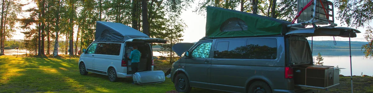 Camper auf einer Wiese vor einem See